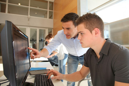 Lehrer und Schüler vor einem Computerbildschirm